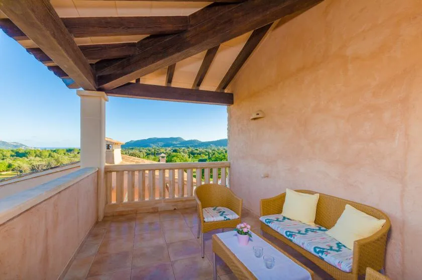 A covered terrace with cushioned seating and a view of the surrounding hills.