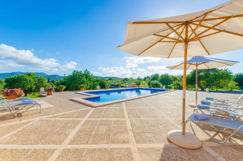 An outdoor pool area with lounge seating and large shade umbrellas.