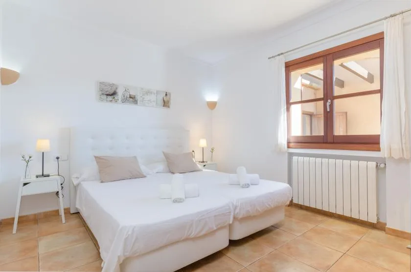 A bright bedroom with two beds and a window above a radiator.