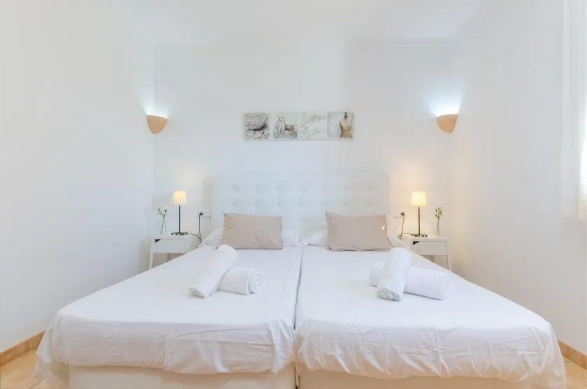 A bright bedroom with two beds and matching bedside tables.