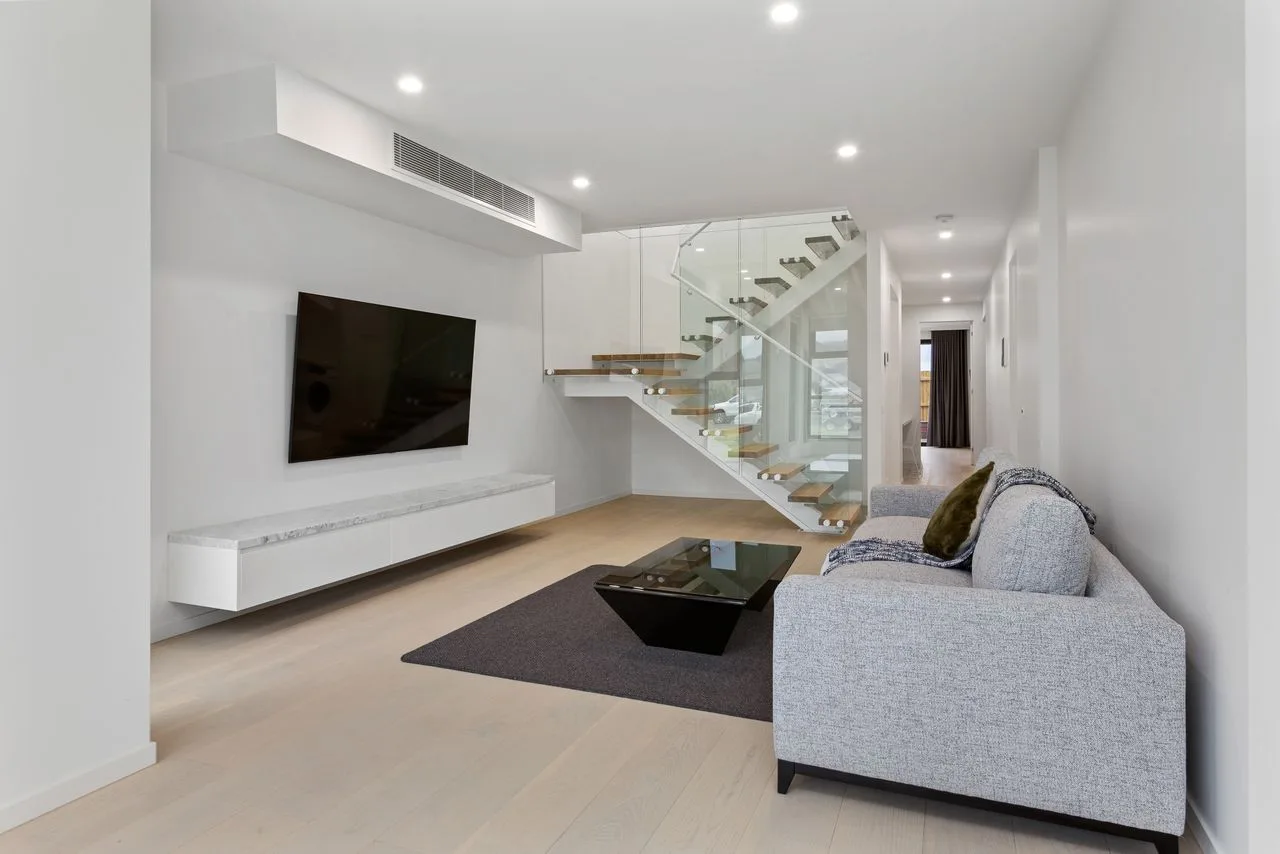 Una sala de estar moderna con asientos, una mesa de centro y una escalera.