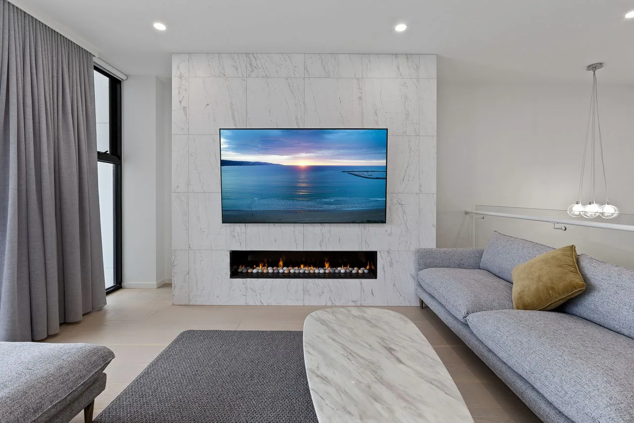 Una sala de estar moderna con un televisor sobre una chimenea y asientos.
