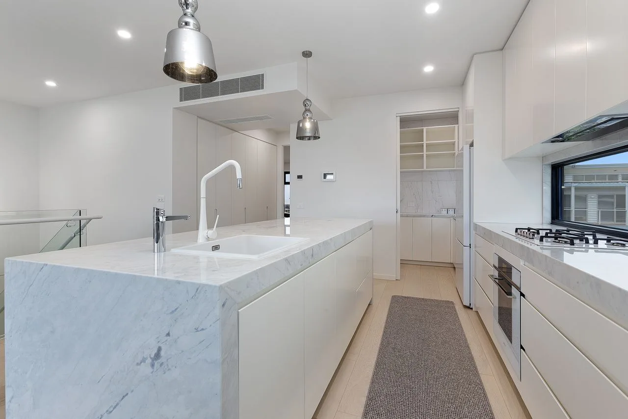Una cocina moderna y luminosa con una isla grande y electrodomésticos integrados.