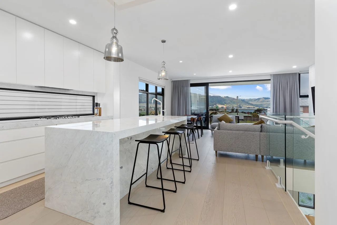 Una cocina y sala de estar de planta abierta con una barra larga y asientos.