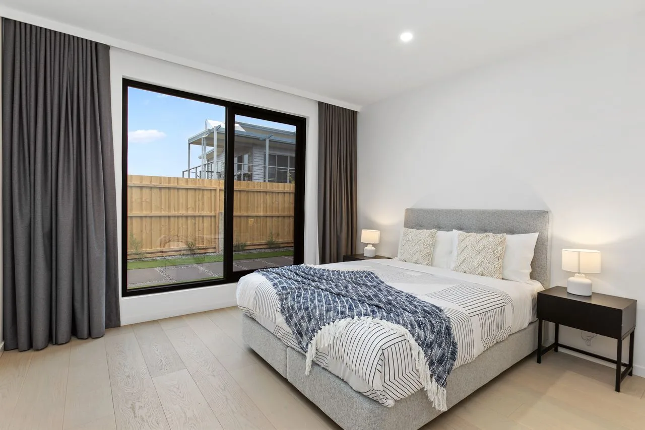 Un dormitorio con una cama grande junto a una ventana y cortinas oscuras.