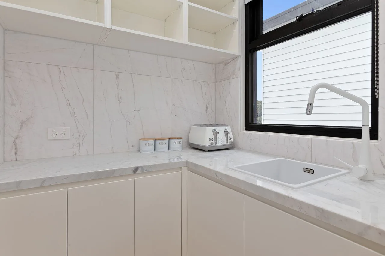 Una encimera de cocina luminosa con un fregadero bajo una ventana amplia.