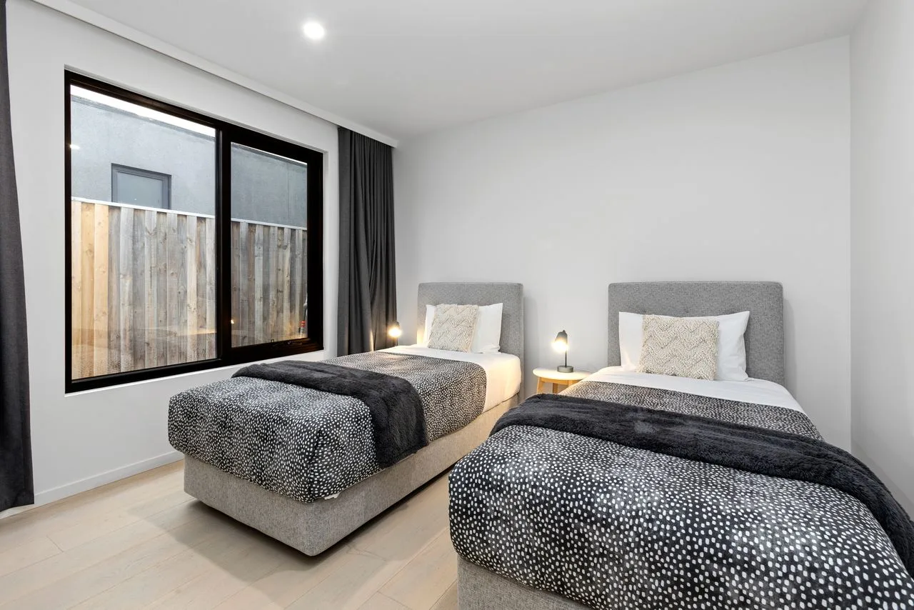A bright bedroom with two beds and a large window.