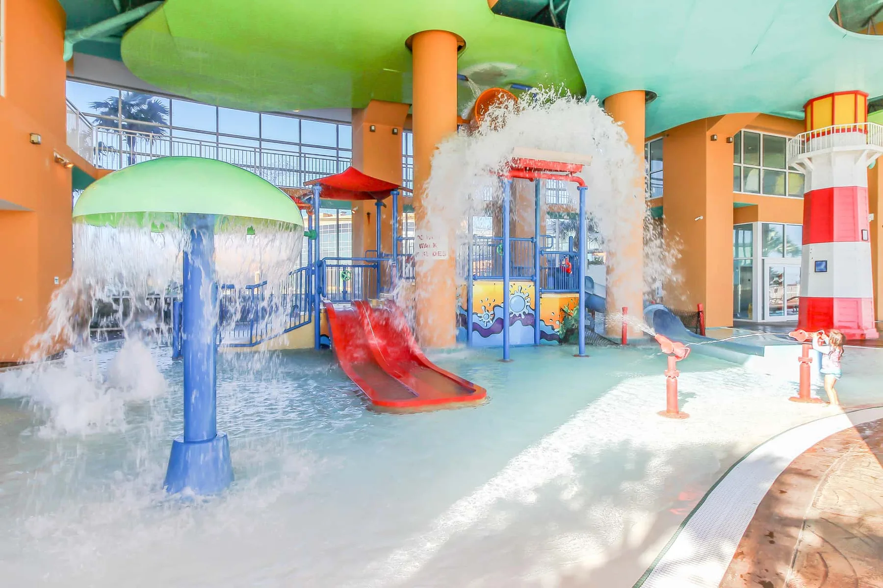 Una zona de juegos acuáticos interior cuenta con toboganes y fuentes de agua.