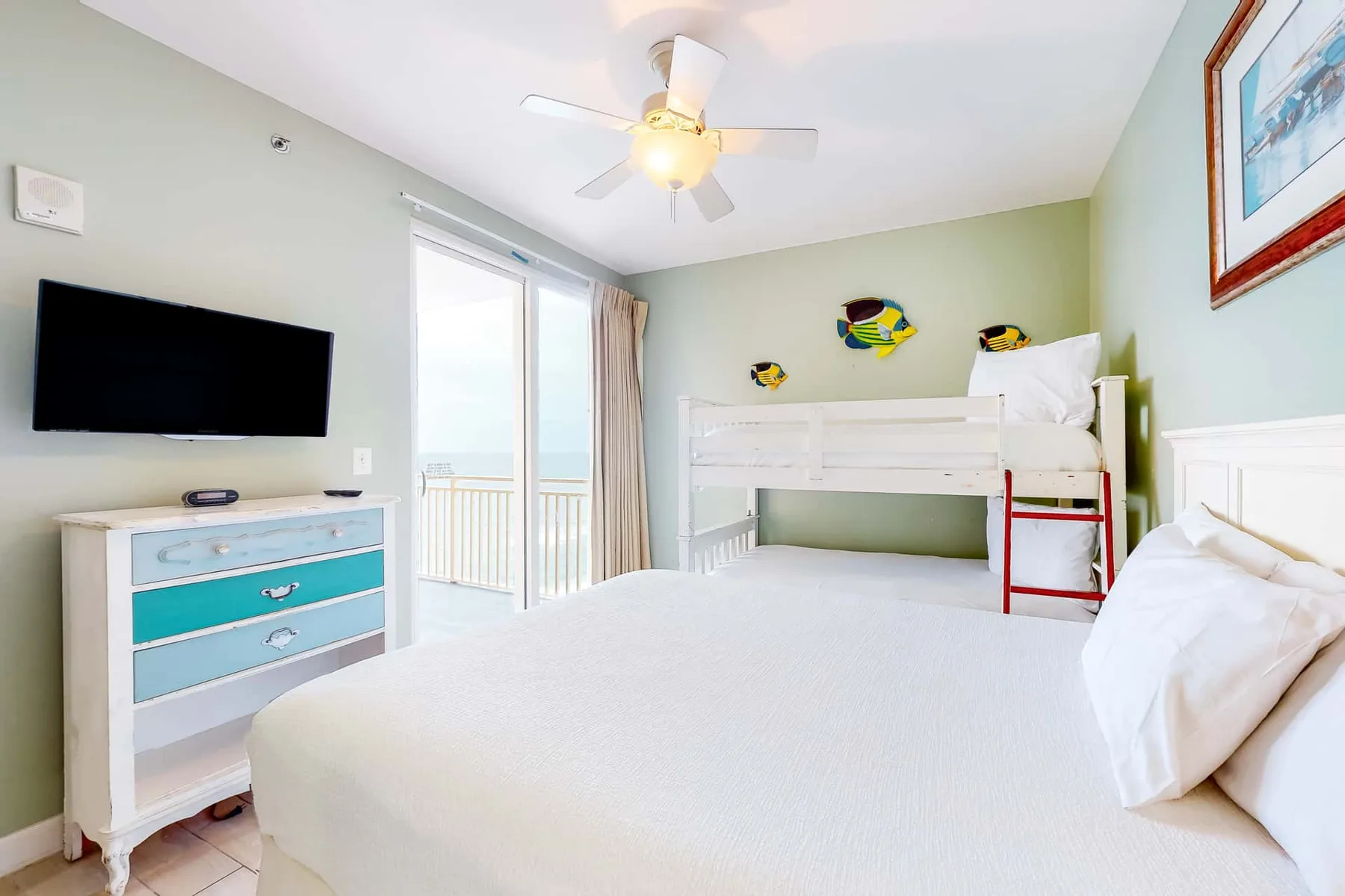 Un dormitorio luminoso con una cama grande, una litera y un televisor.