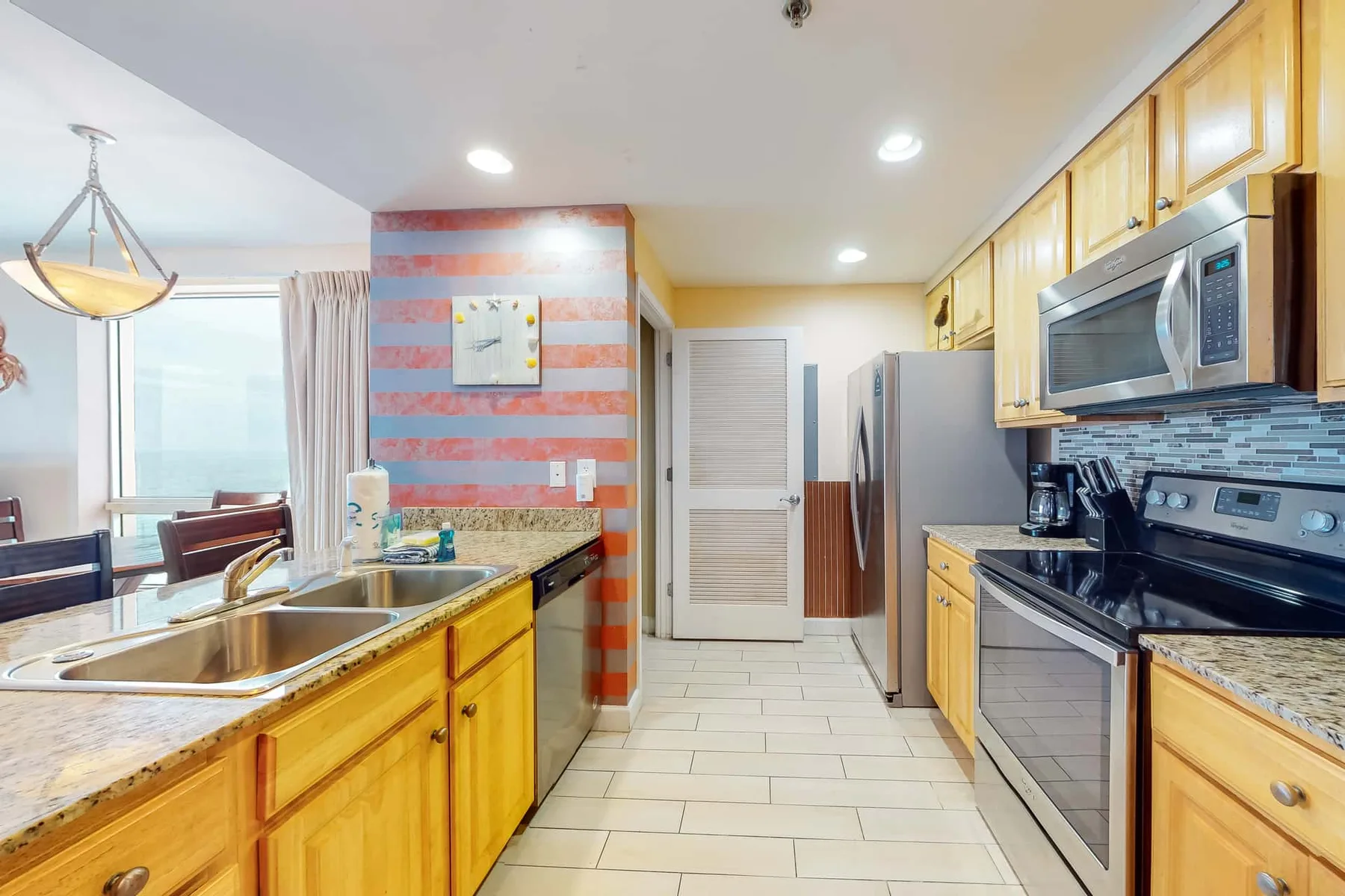Una cocina luminosa con gabinetes de madera, electrodomésticos de acero inoxidable y una isla central.