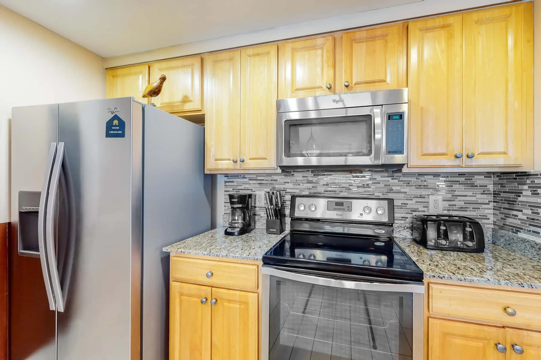 Una cocina con gabinetes de madera, electrodomésticos de acero inoxidable y un salpicadero de azulejos.