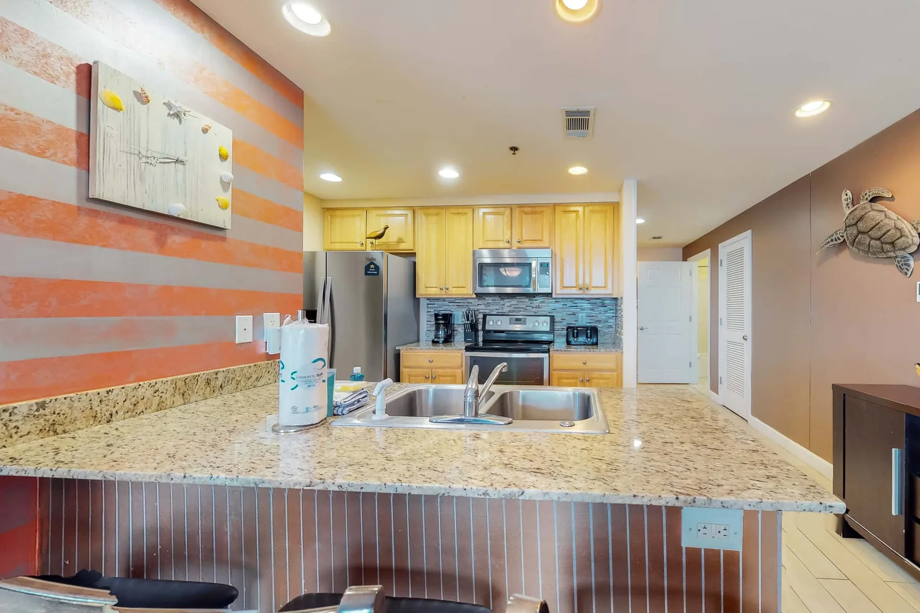 Una cocina con gabinetes de madera clara y una isla grande con patrón de piedra.