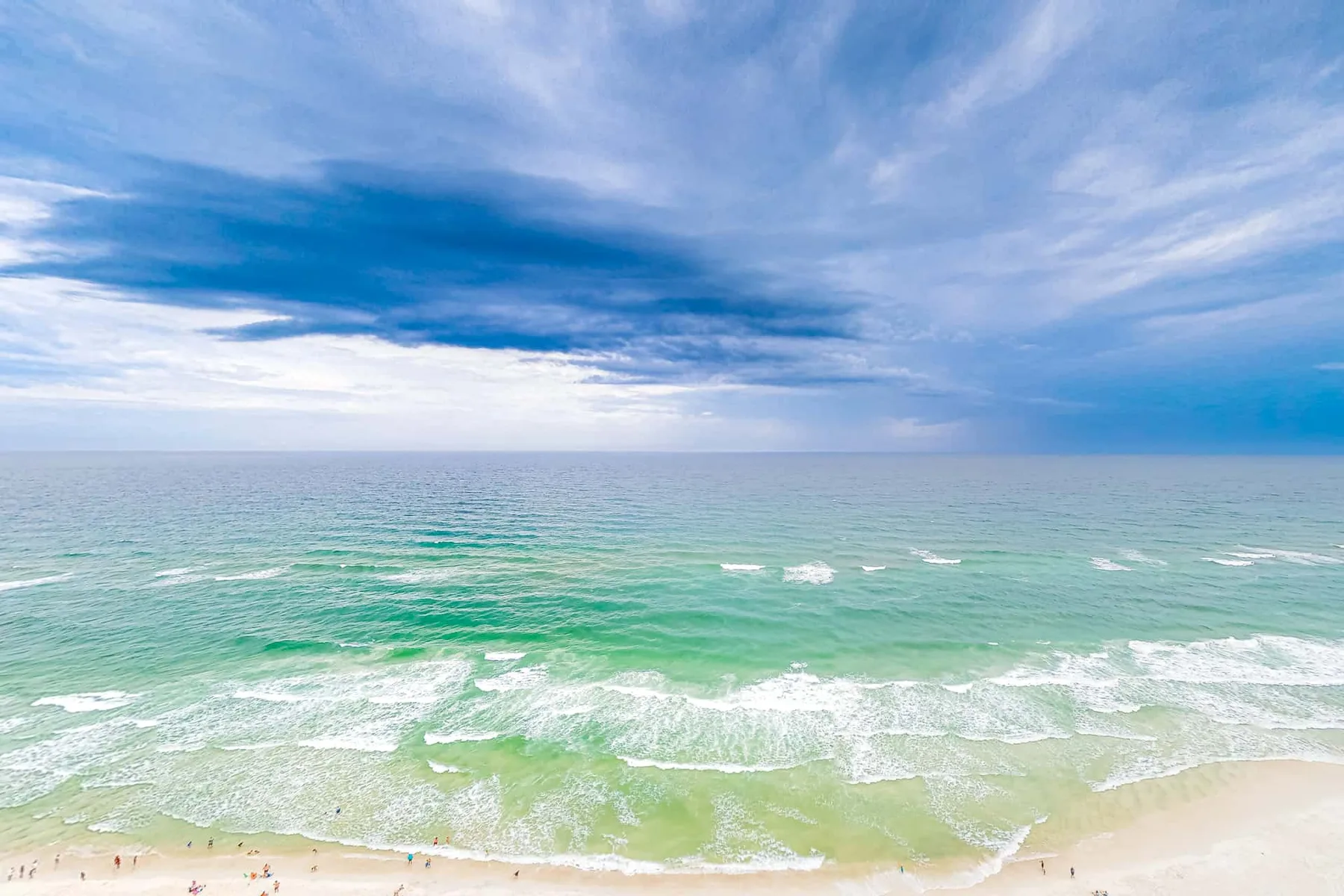 Una playa con olas suaves bajo un cielo nublado.