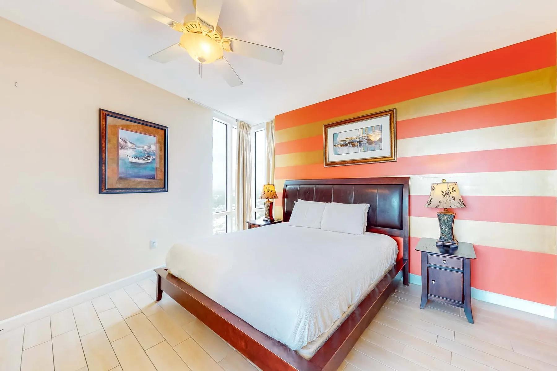 Un dormitorio con una cama junto a una pared pintada con franjas horizontales de colores.