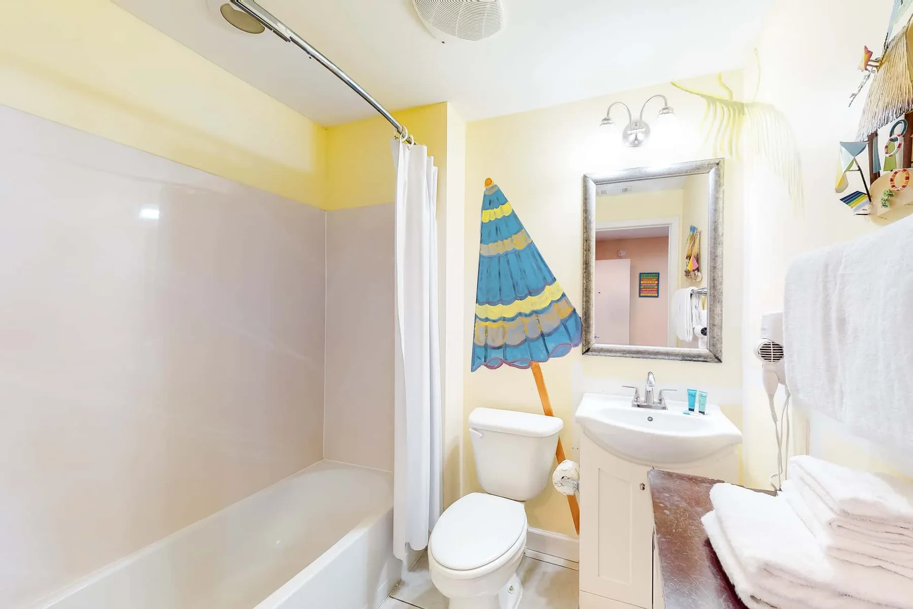 Un baño luminoso con bañera, inodoro y lavabo.