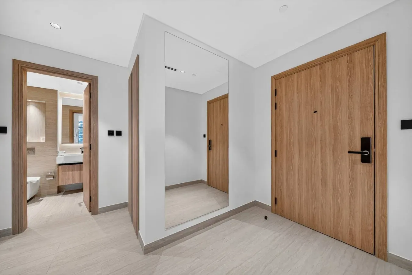 A bright entryway with light wood doors and a full-length mirror.