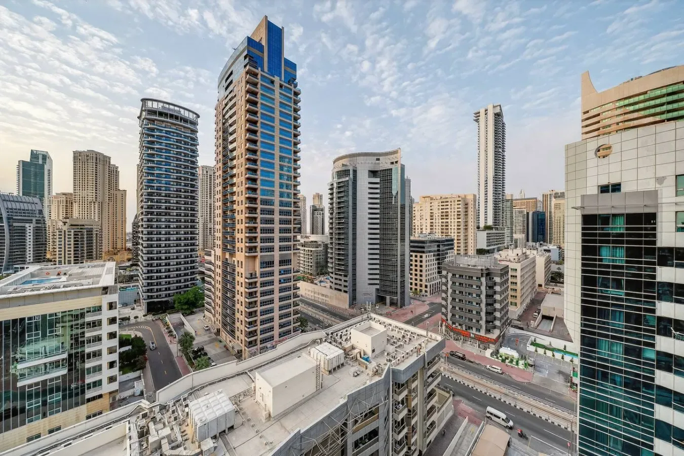 A cityscape of modern high-rise buildings beneath a partly cloudy sky.