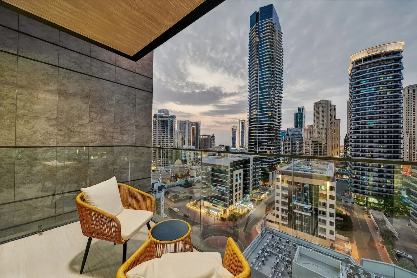 A balcony seating area overlooks a city skyline with high-rise buildings.