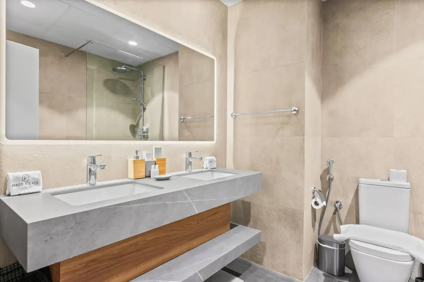Un baño moderno con un amplio lavabo, espejo de pared, ducha e inodoro.