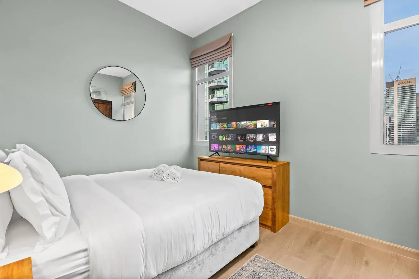 Un dormitorio con una cama tendida, una cómoda y un televisor.