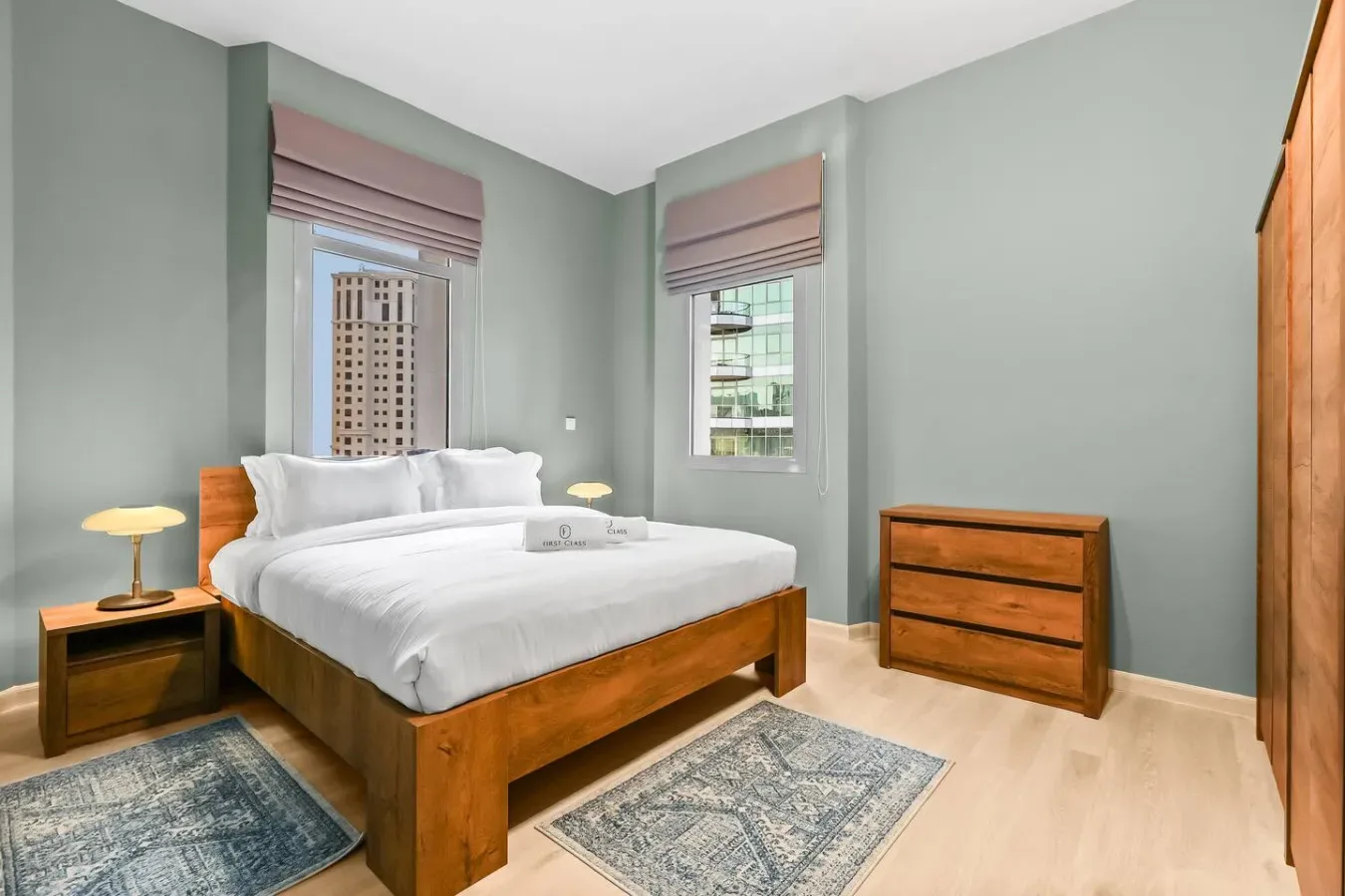 Un dormitorio con cama de madera, mesitas de noche y ventanas con persianas.