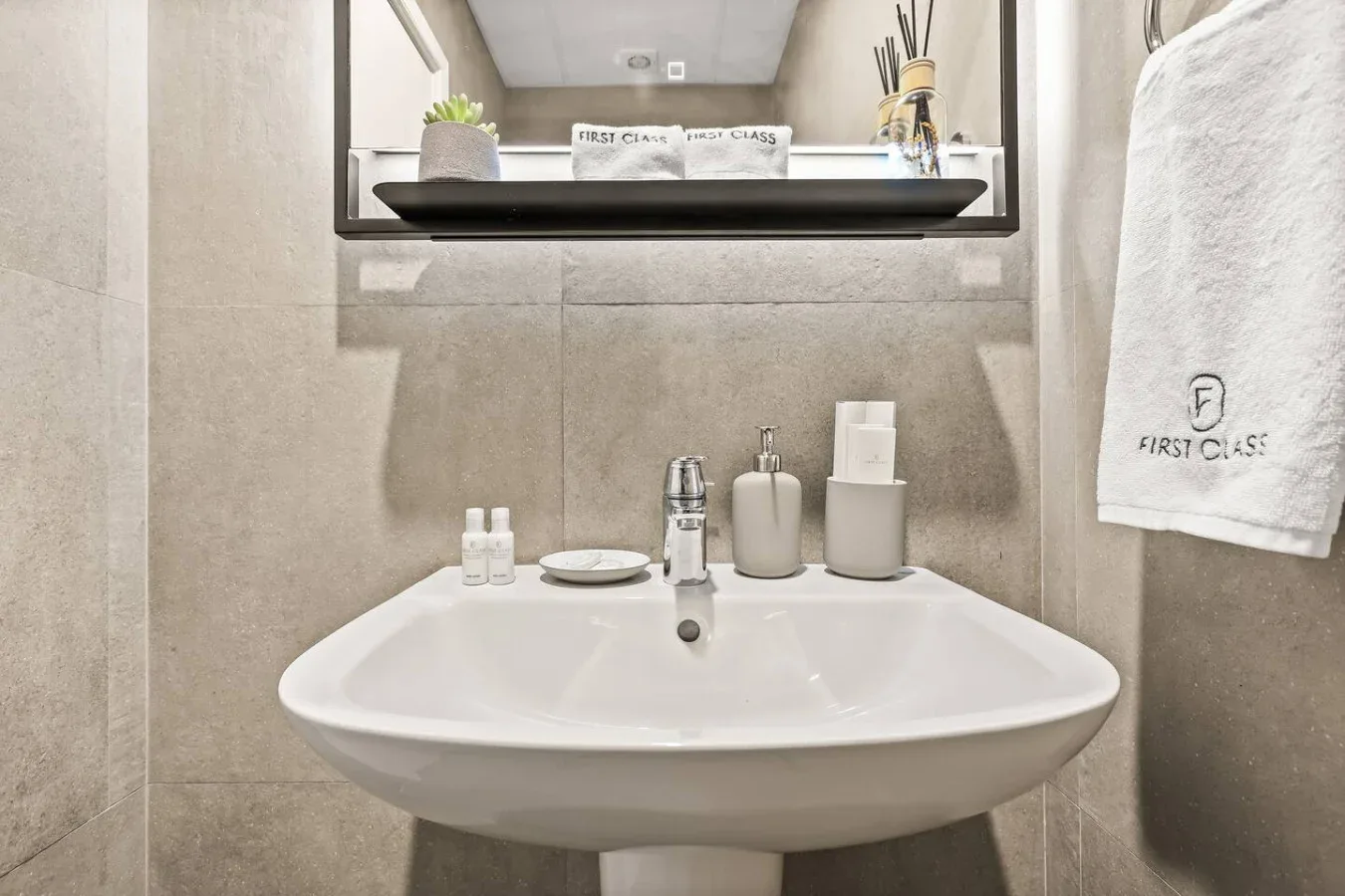 Un lavabo de baño con un lavamanos blanco, artículos de aseo y un espejo.