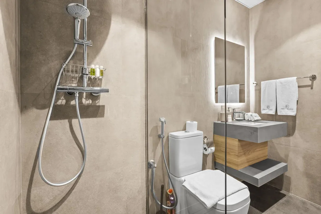 Un baño moderno con ducha, inodoro y lavabo suspendido.