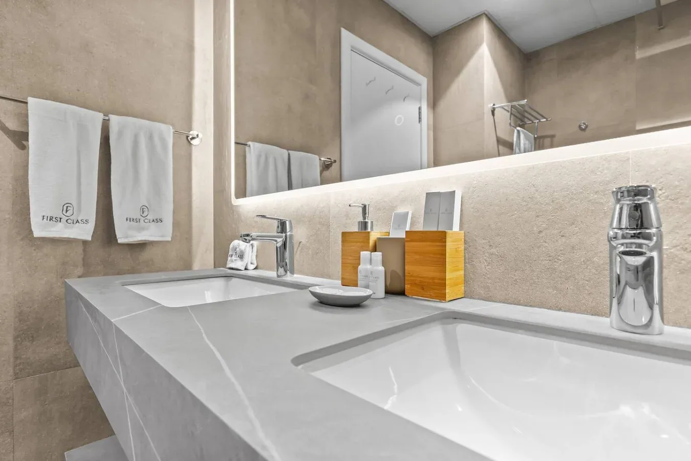 Un tocador de baño moderno con un espejo amplio y una encimera blanca.
