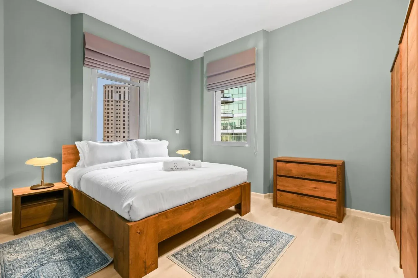 Un dormitorio con una cama de madera, ropa de cama blanca y ventanas con persianas malva.