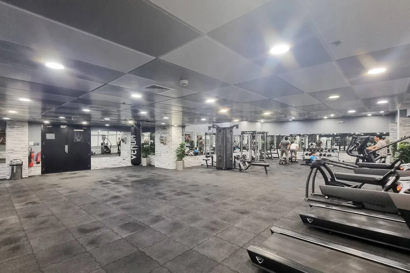 Un gimnasio amplio con máquinas de ejercicio y equipos para entrenar con pesas.