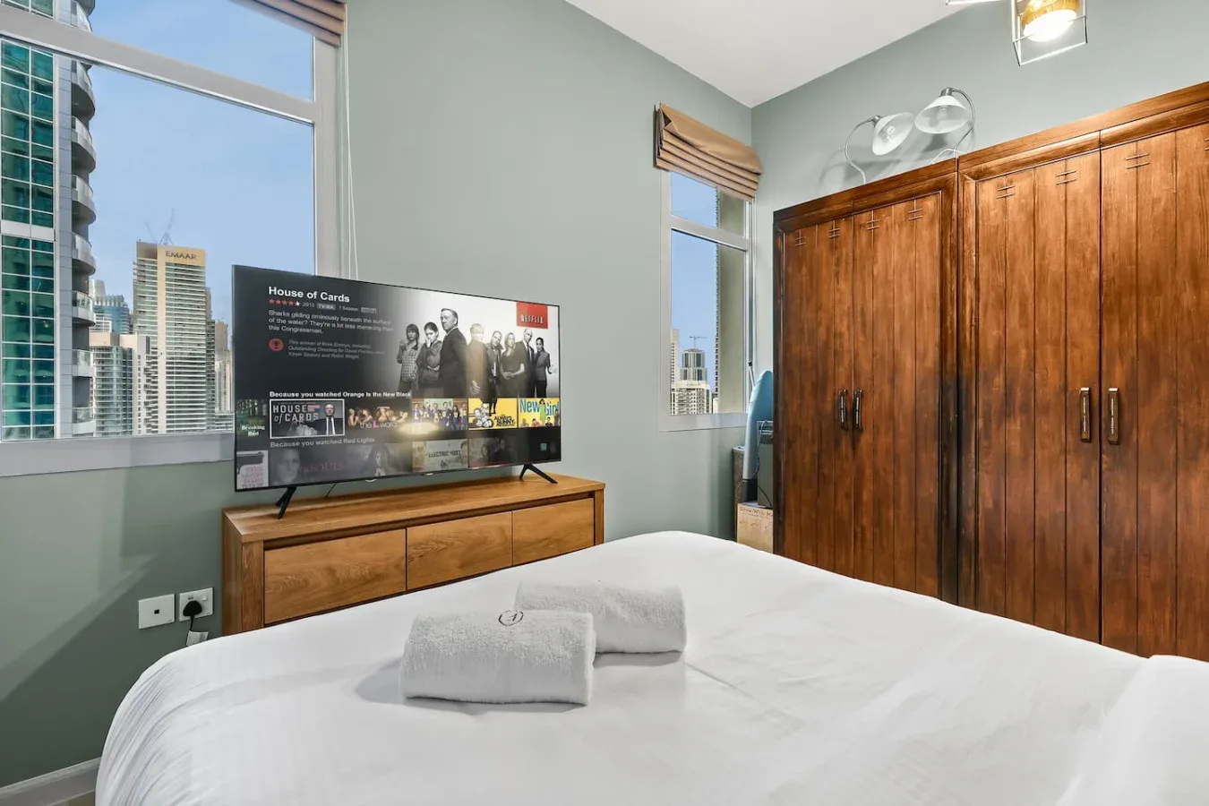 Un dormitorio con una cama bien tendida, un armario de madera y un televisor.