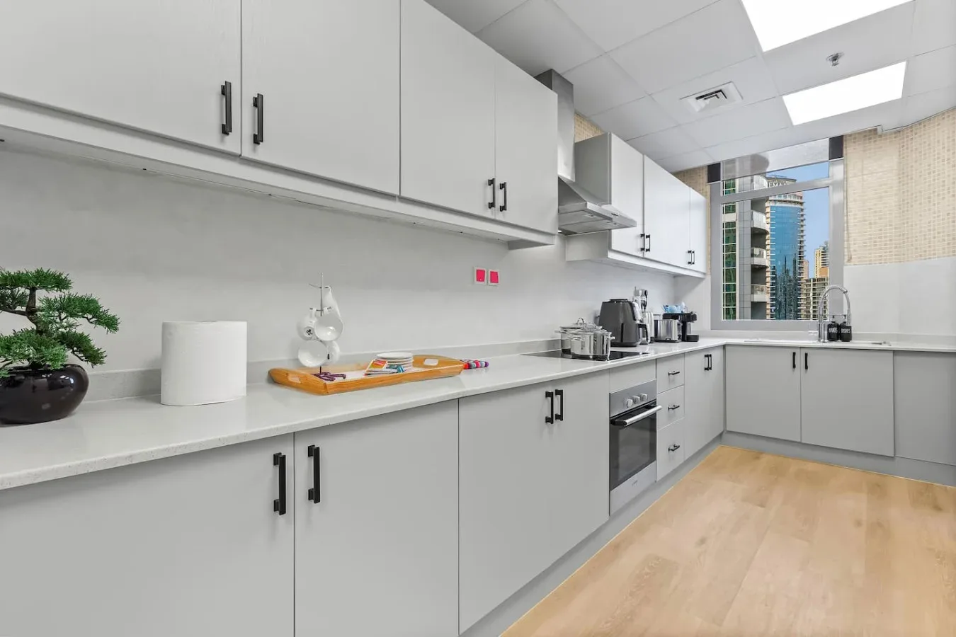 Una cocina moderna con gabinetes blancos, encimeras claras y piso de madera.