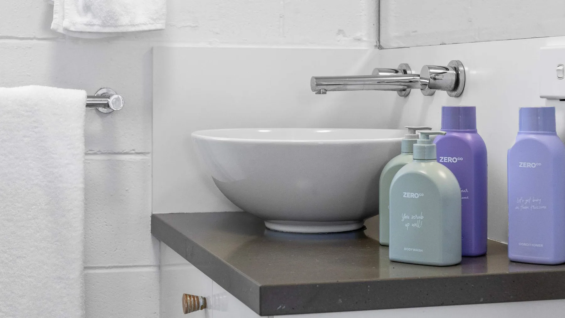 Un lavabo de baño con dispensadores de jabón y una toalla en la pared.