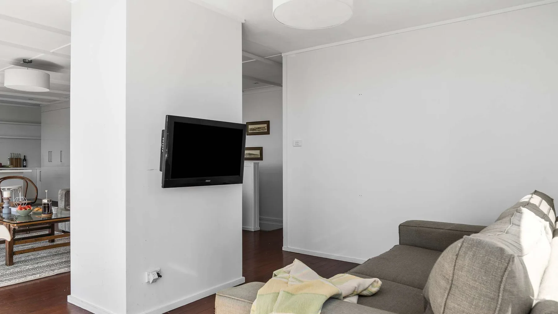 Sala de estar con un televisor y asientos junto a una puerta abierta.