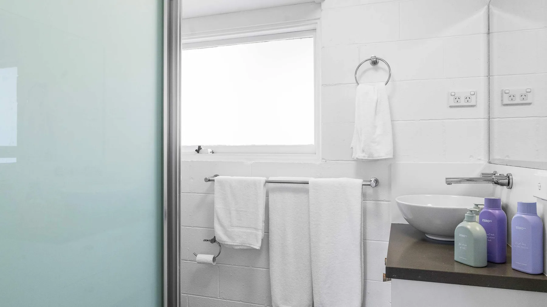 Un baño luminoso con lavabo, espejo y toallas blancas.