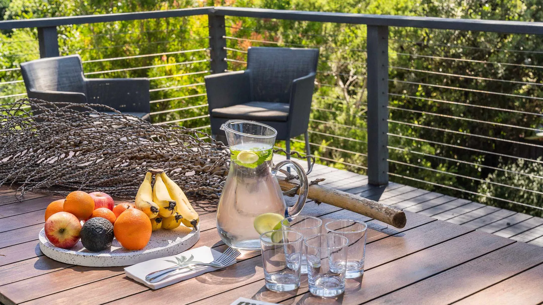 Una terraza exterior con asientos y una mesa con fruta y bebidas.