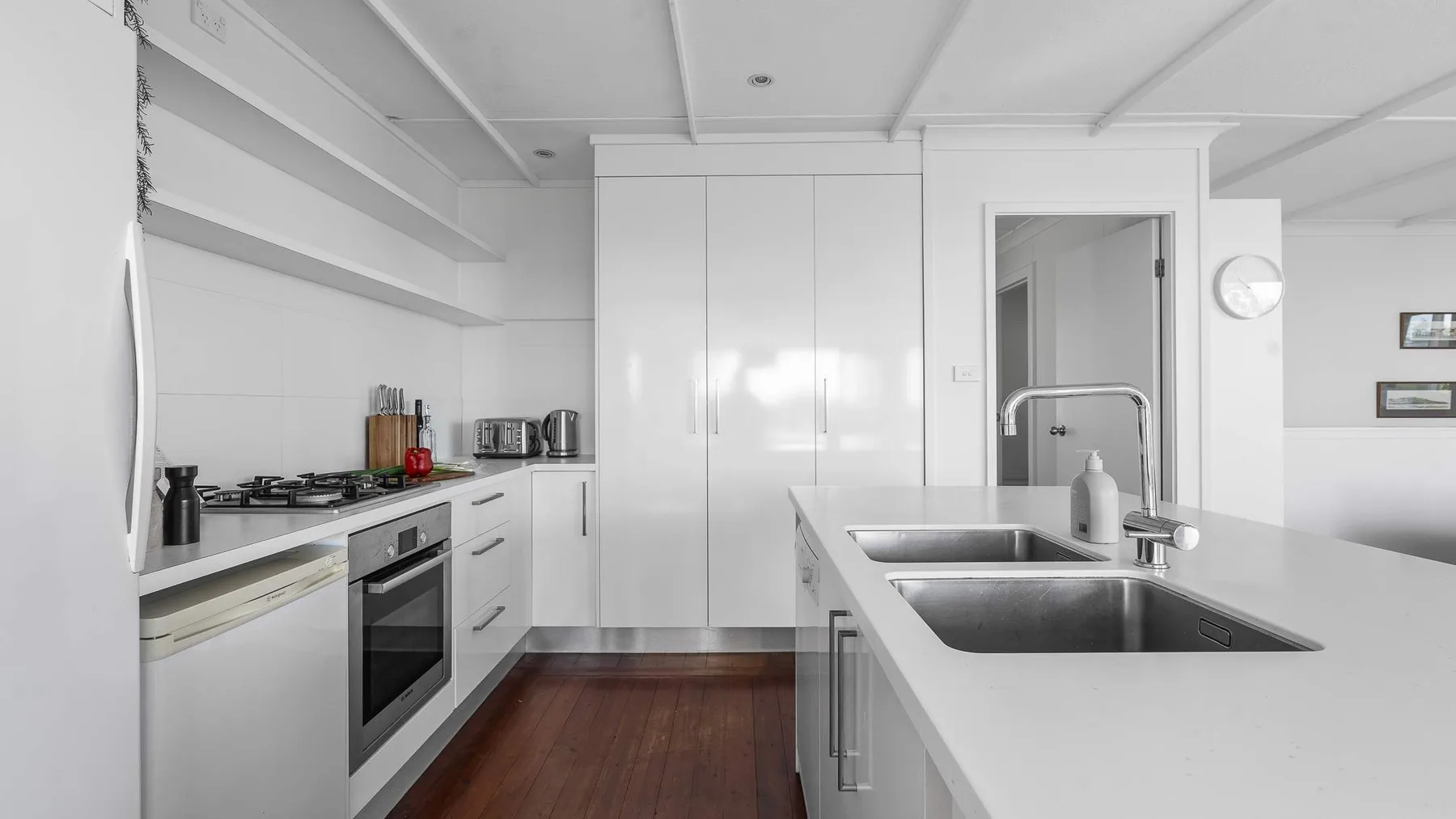 Una cocina blanca y luminosa con una isla central y zona de cocción integrada.