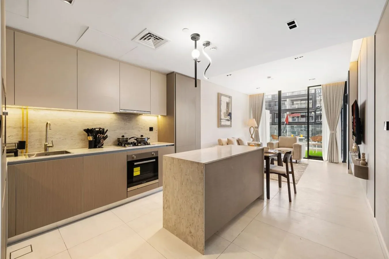 Una cocina y comedor modernos con una isla central y grandes ventanas.