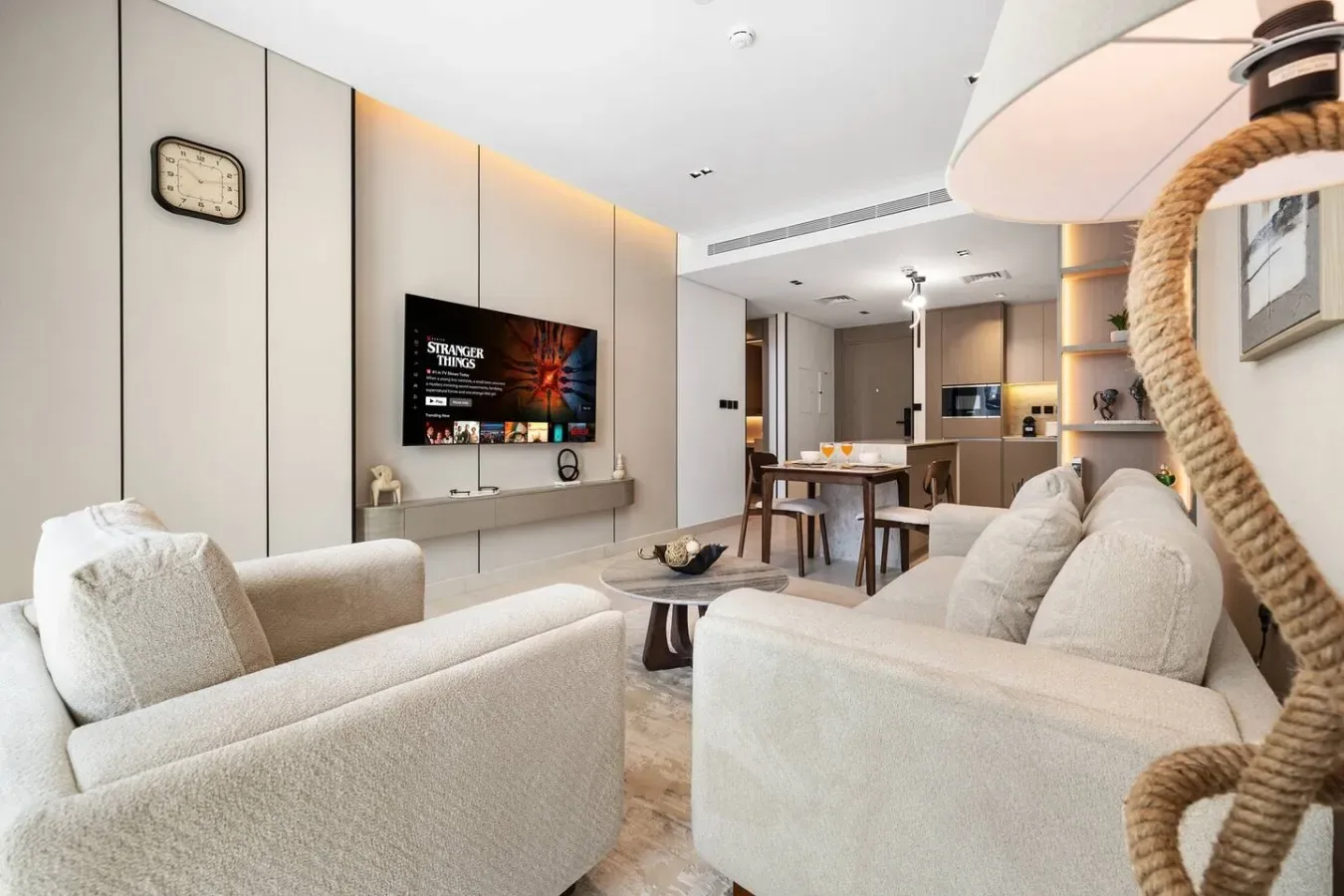 Una sala luminosa con asientos claros y un comedor al fondo.