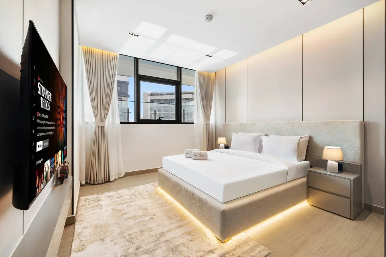 Un dormitorio con una cama grande junto a una ventana con cortinas.