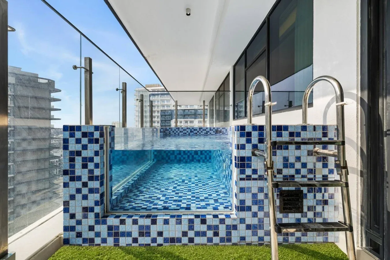 Una pequeña piscina alicatada está junto a ventanales.