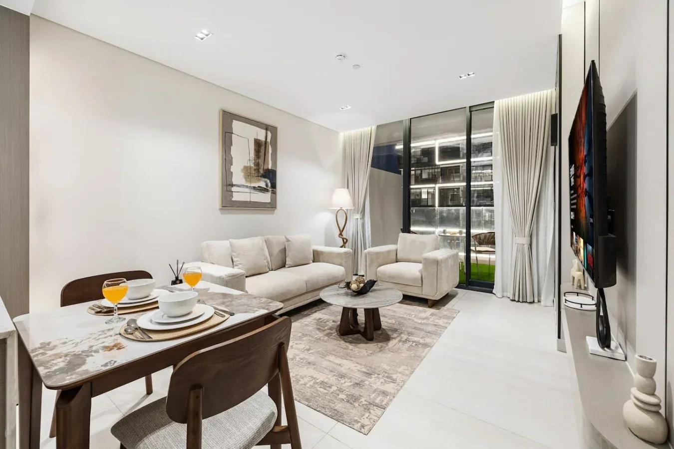 Una sala luminosa con mesa de comedor, asientos y grandes ventanales.