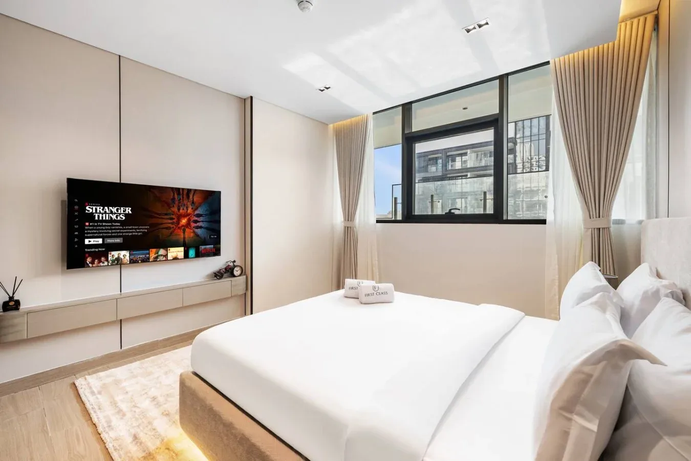 Un dormitorio luminoso con una cama grande, una ventana y un televisor en la pared.
