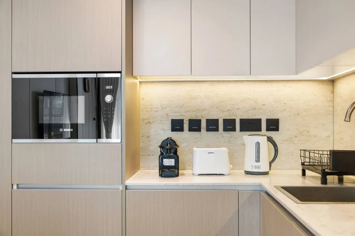 Una encimera de cocina moderna tiene pequeños electrodomésticos junto a un fregadero.
