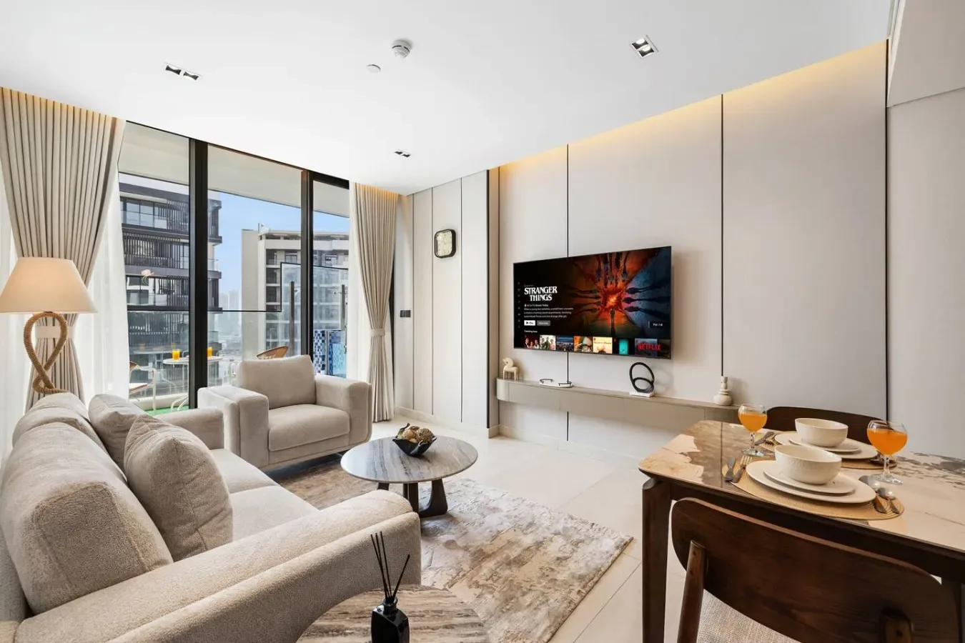 Una sala luminosa con asientos, grandes ventanas y un televisor.