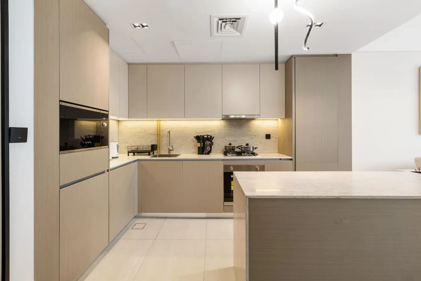 Una cocina moderna con electrodomésticos integrados, gabinetes claros y una isla central.
