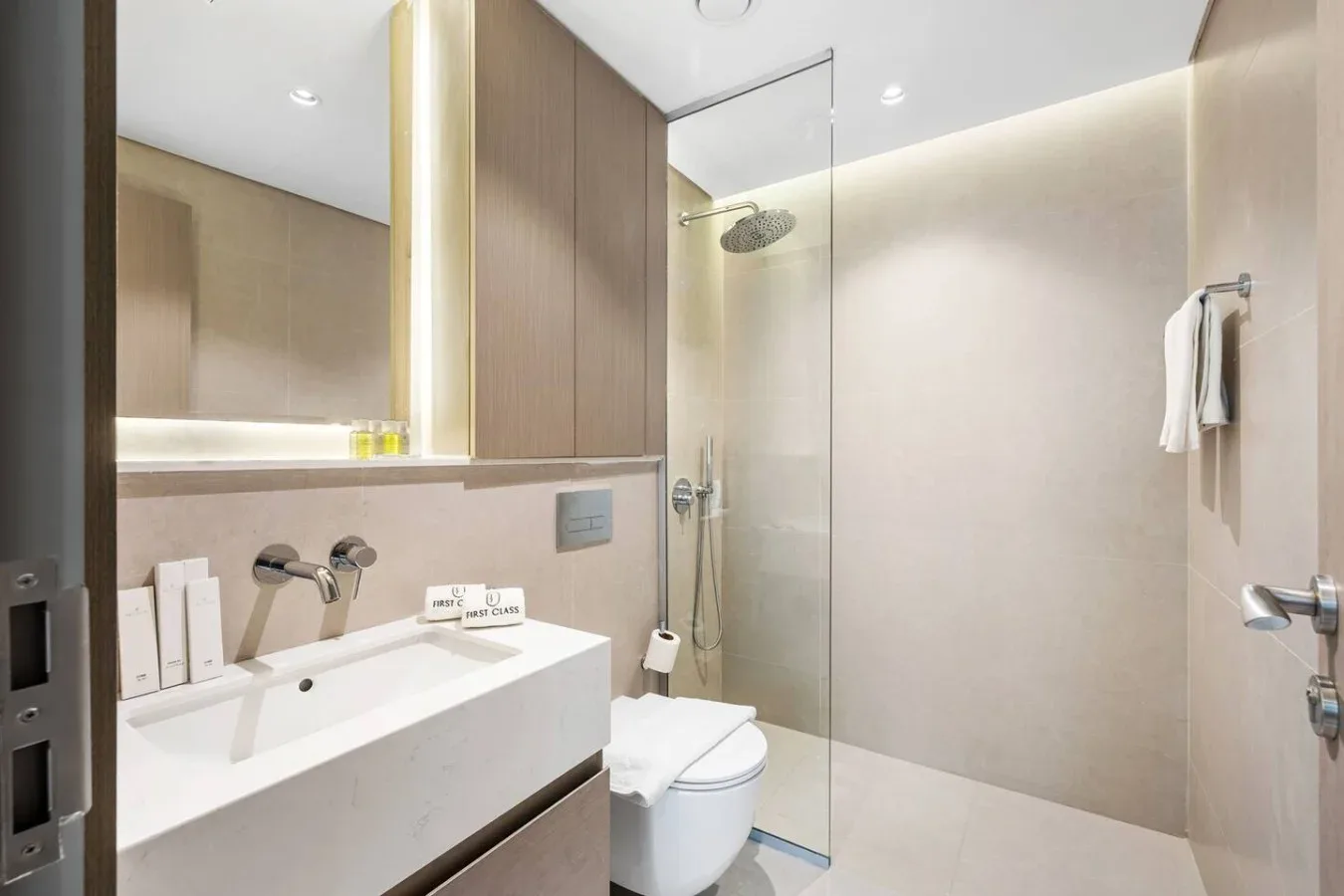 Un baño luminoso con lavabo, inodoro y ducha de cristal.