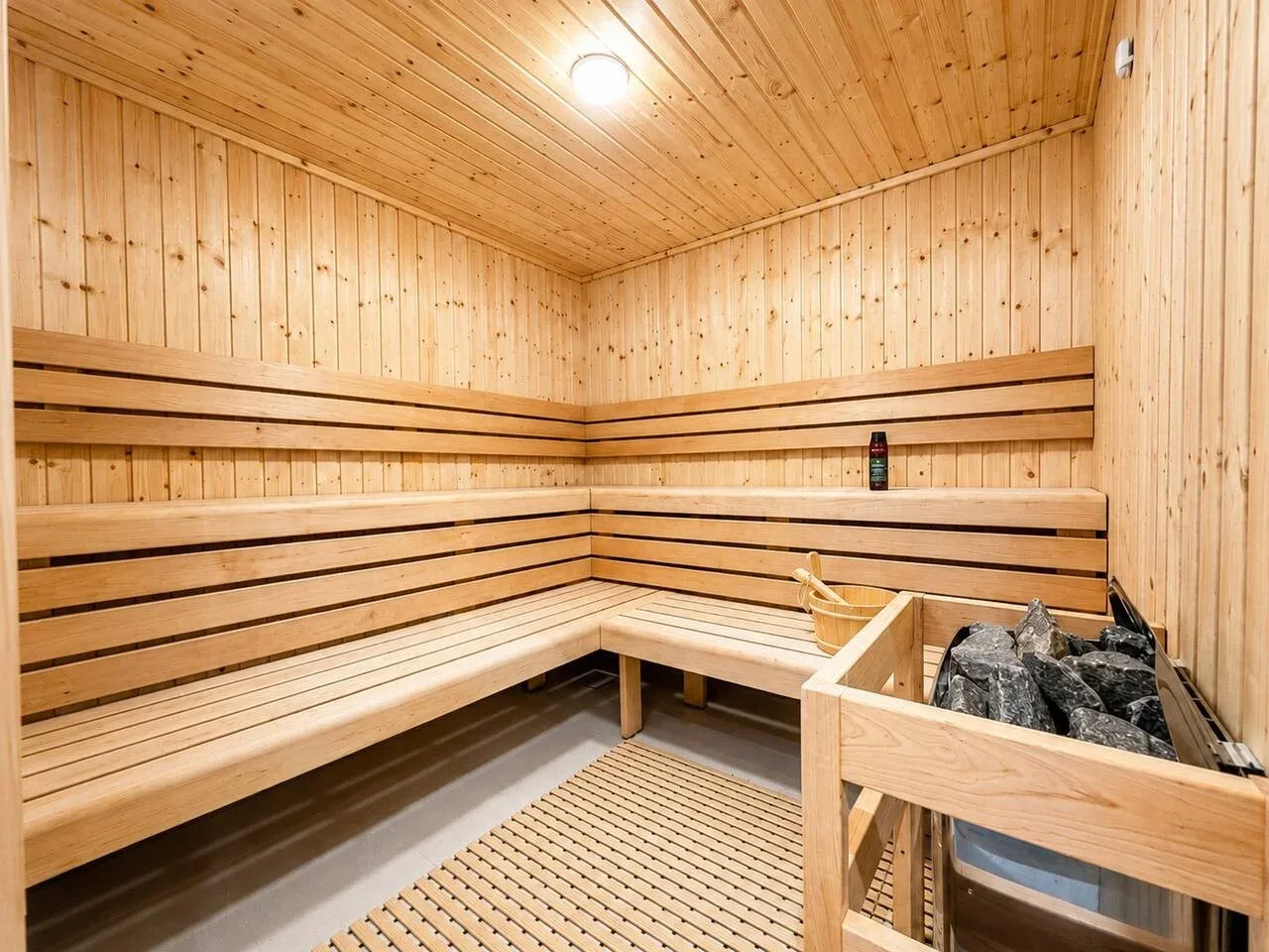 Una sauna revestida de madera, con bancos escalonados y un calentador de piedras.
