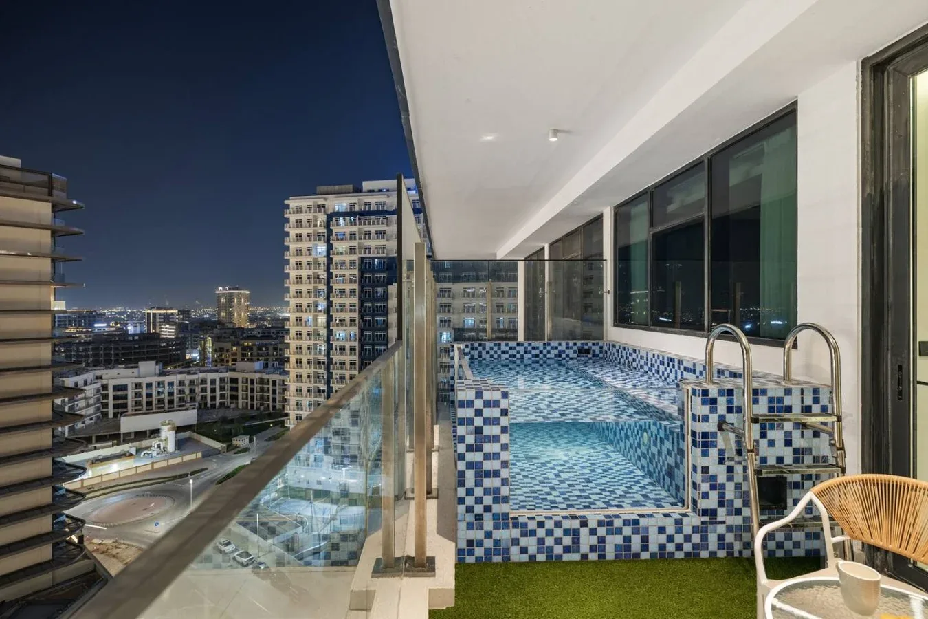 Una piscina en la azotea de noche ofrece vistas de edificios iluminados.
