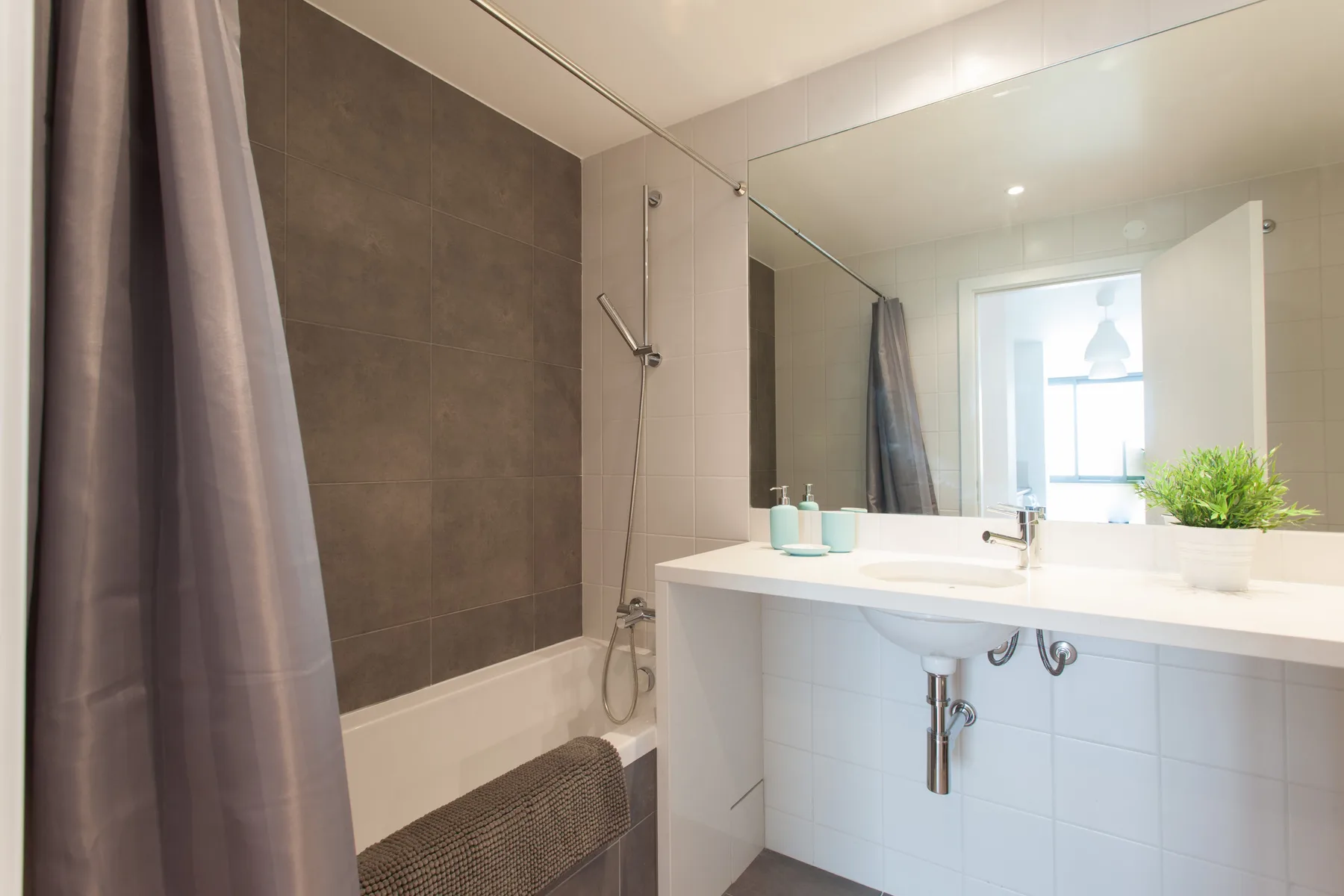 A bright bathroom with a bathtub, shower, and sink.